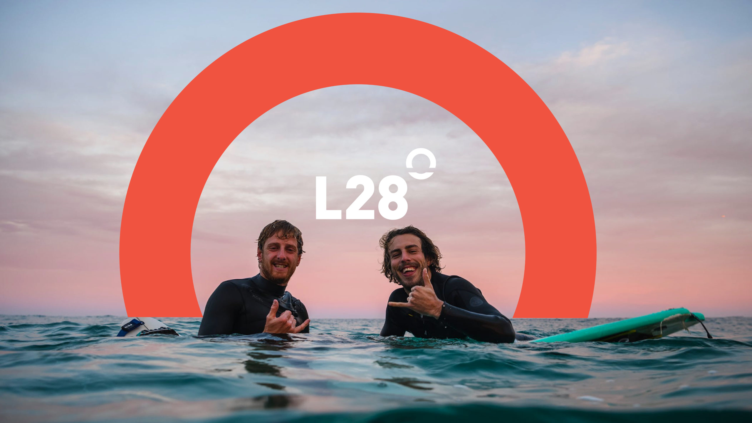 Two guys bobbing on surfboards in the ocean and giving the camera shakas. Over them is the L28 Logo.