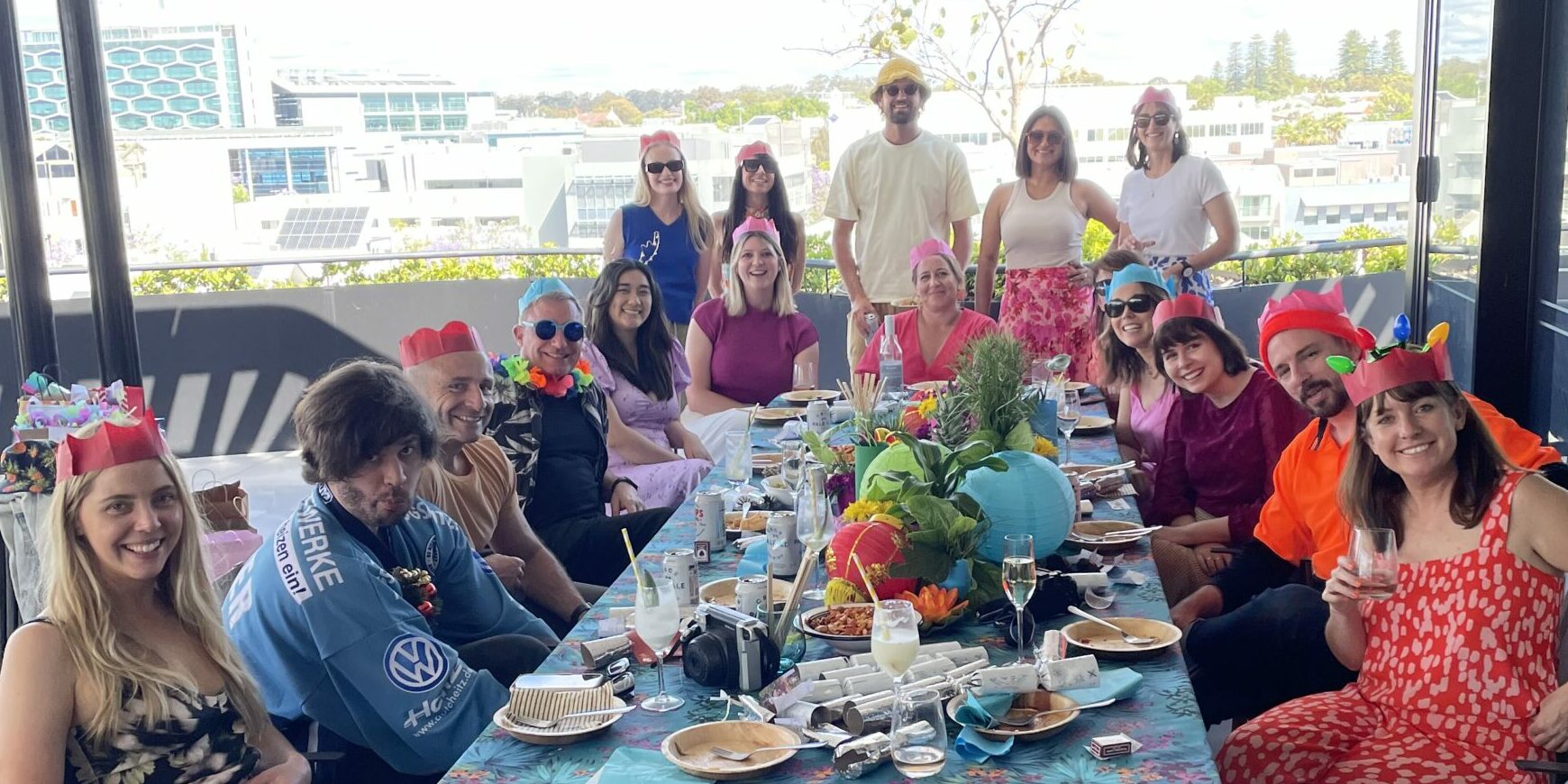 Anthologie team in Christmas hats enjoying lunch together at a long table.